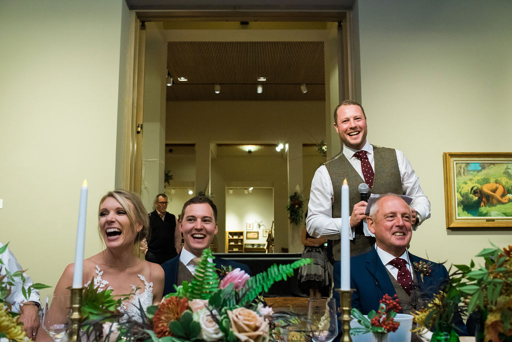A bride and groom are toasted by a groomsman
