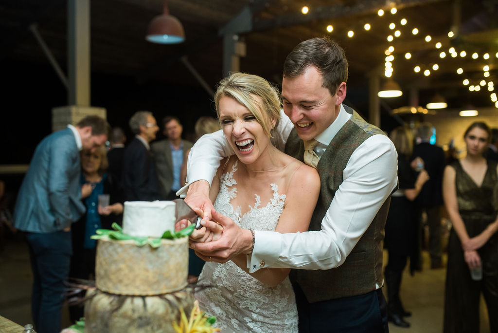 A bride and groom cut their cheese cake at their wedding