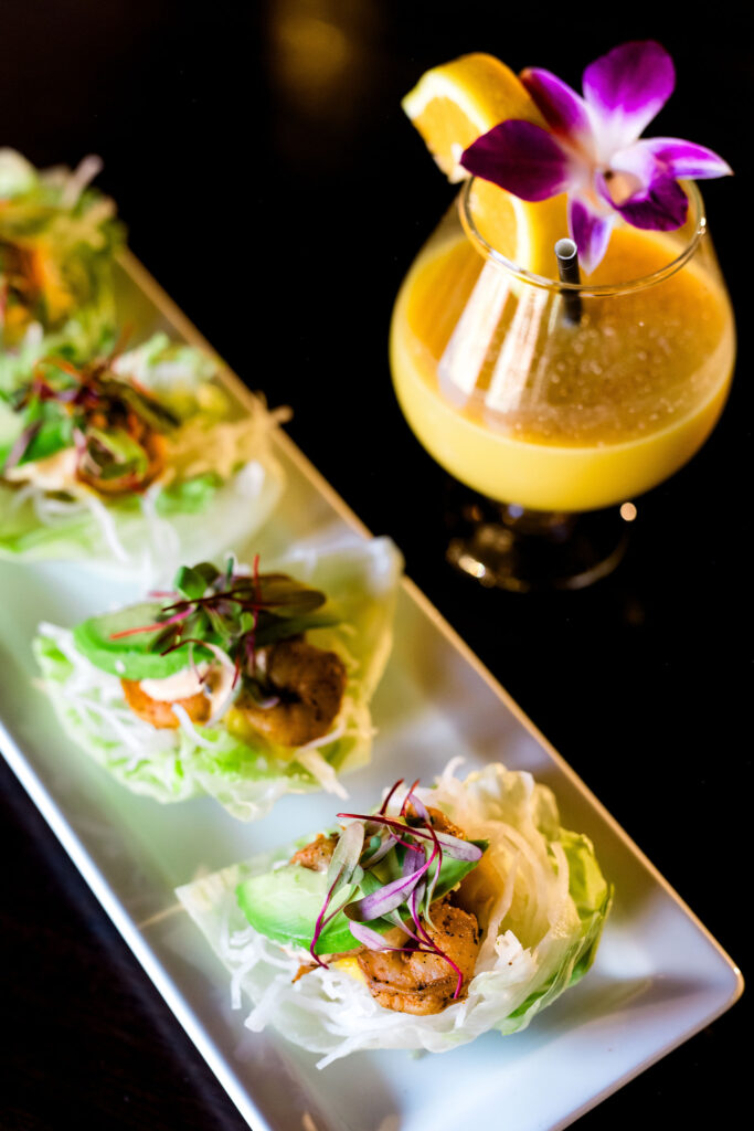 Kkalanis.2024-117 Colorful lettuce wraps served with a tropical cocktail garnished with an orchid and orange slice at Kalani’s Lake Tahoe, a local favorite for Pacific Rim cuisine.