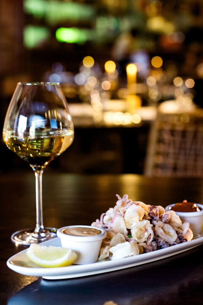 Kkalanis.2024-159 Crispy calamari appetizer with dipping sauces and a glass of white wine at Kalani’s Lake Tahoe, offering upscale dining in South Lake Tahoe’s Heavenly Village