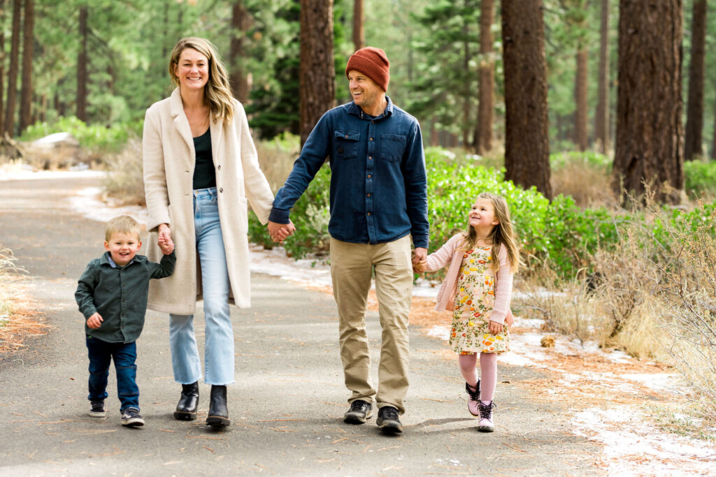 Locals-guide-to-lake-tahoe-94 Family of four walking hand-in-hand through Rabe Meadows forest trail near Lake Tahoe, enjoying a kid-friendly outdoor hike surrounded by pine trees.
