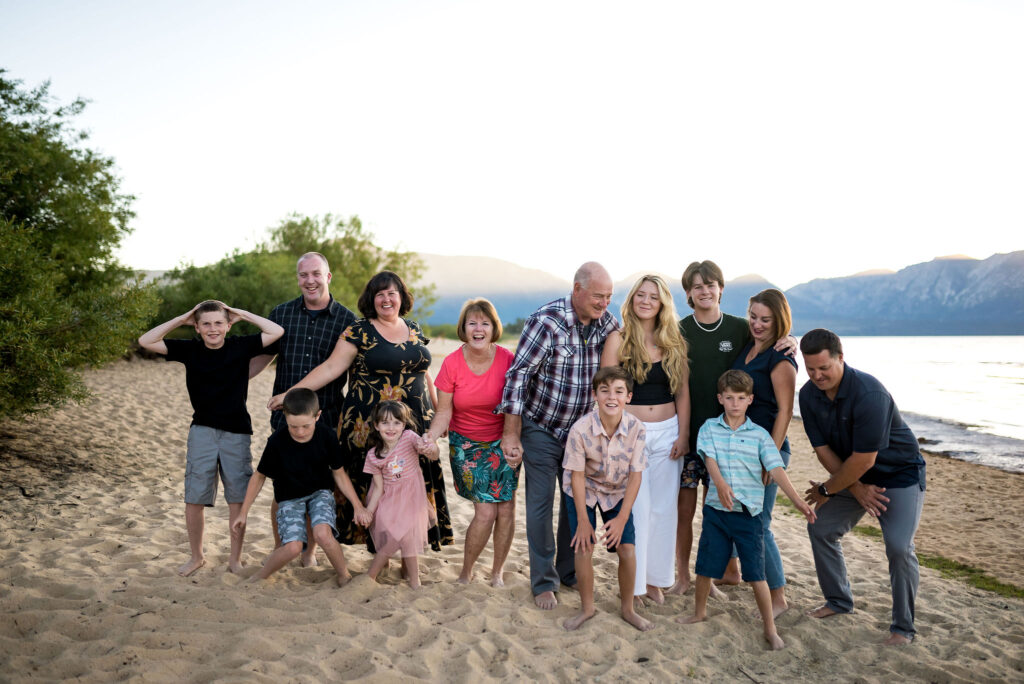 best-locations-for-family-portraits-in-south-lake-tahoe-66 A large extended family poses playfully on the sand at a local secret beach in South Lake Tahoe.